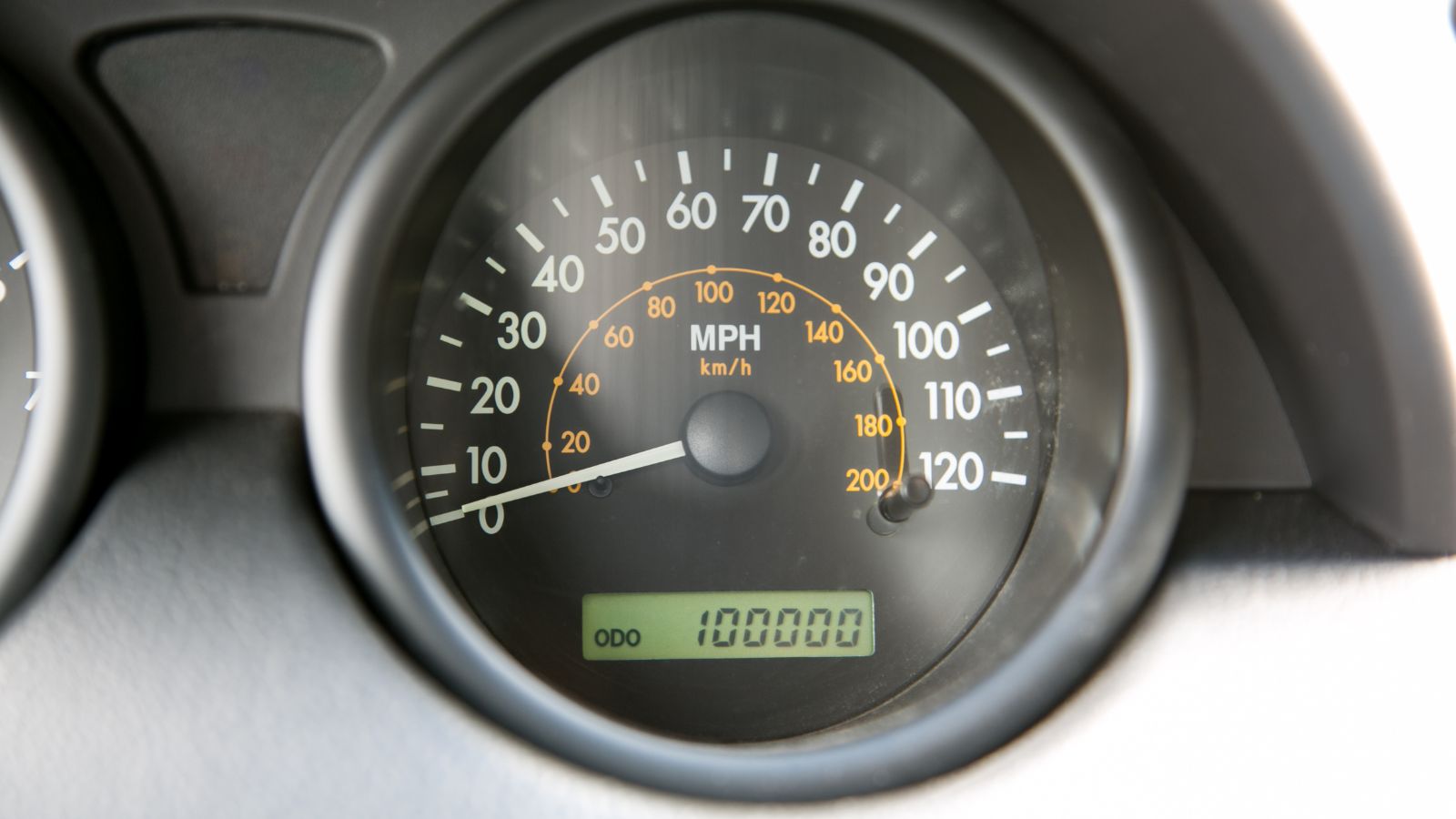 Car dashboard odometer showing 100,000 miles