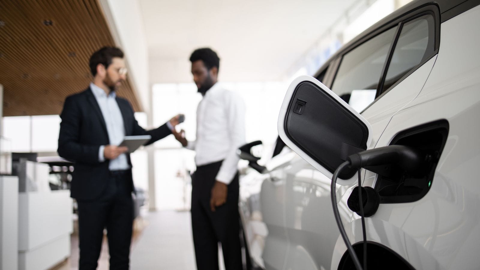 Car salesman discusses electric SUV with businessman