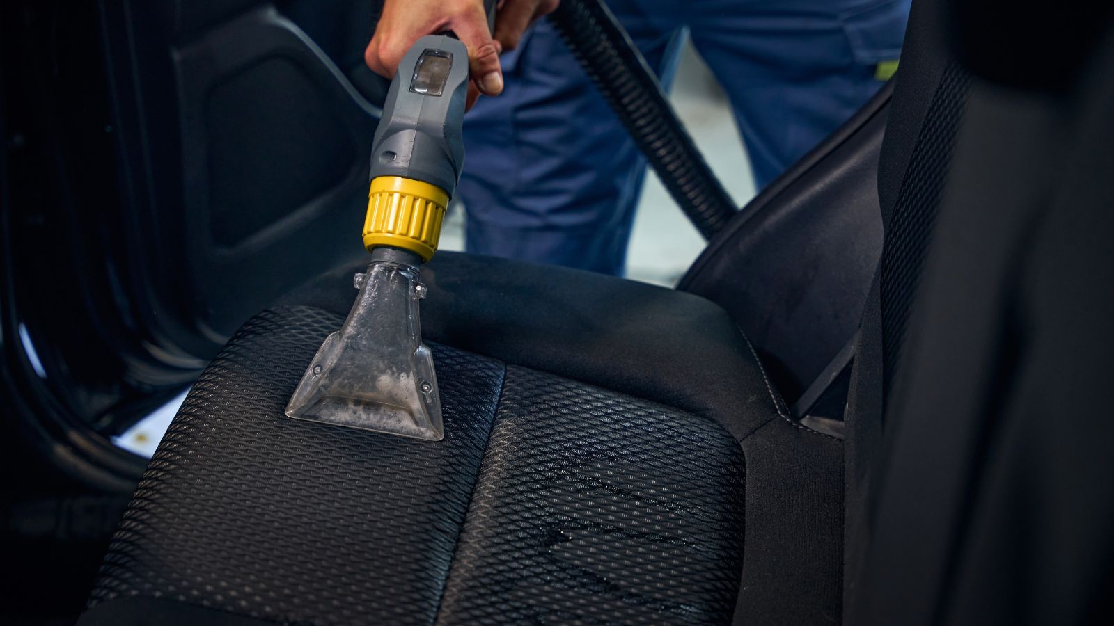 Detailing specialist cleans the interior of car with vacuum cleaner