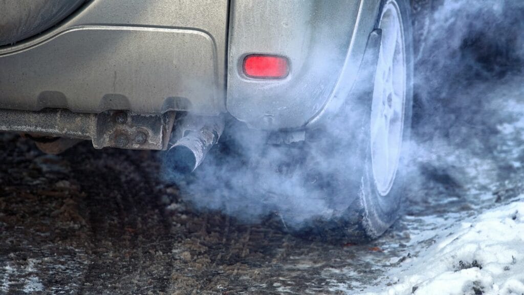 Blue exhaust smoke. Car engine smoking. Smoking exhaust pipe, closeup. Car with gasoline or diesel engine. Engine warming up at idle in winter season