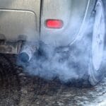 Blue exhaust smoke. Car engine smoking. Smoking exhaust pipe, closeup. Car with gasoline or diesel engine. Engine warming up at idle in winter season