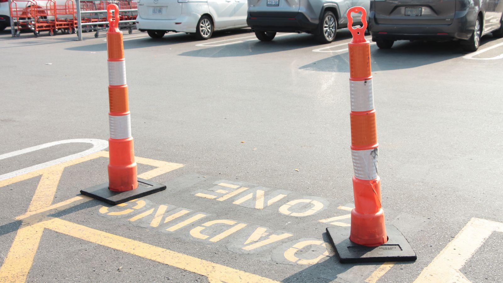 tor, canada - august 16, 2023: stack sticks tall orange white black pylons on top of loading zone writing caption text in parking lot in summer