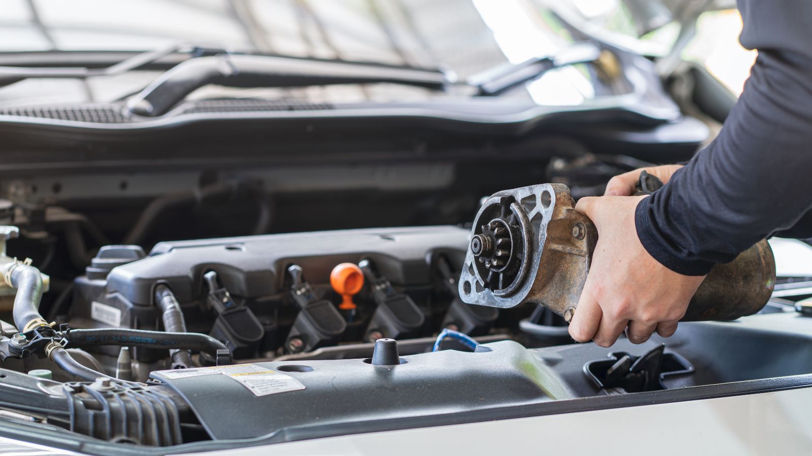 Mechanic man holding starter motor of the car