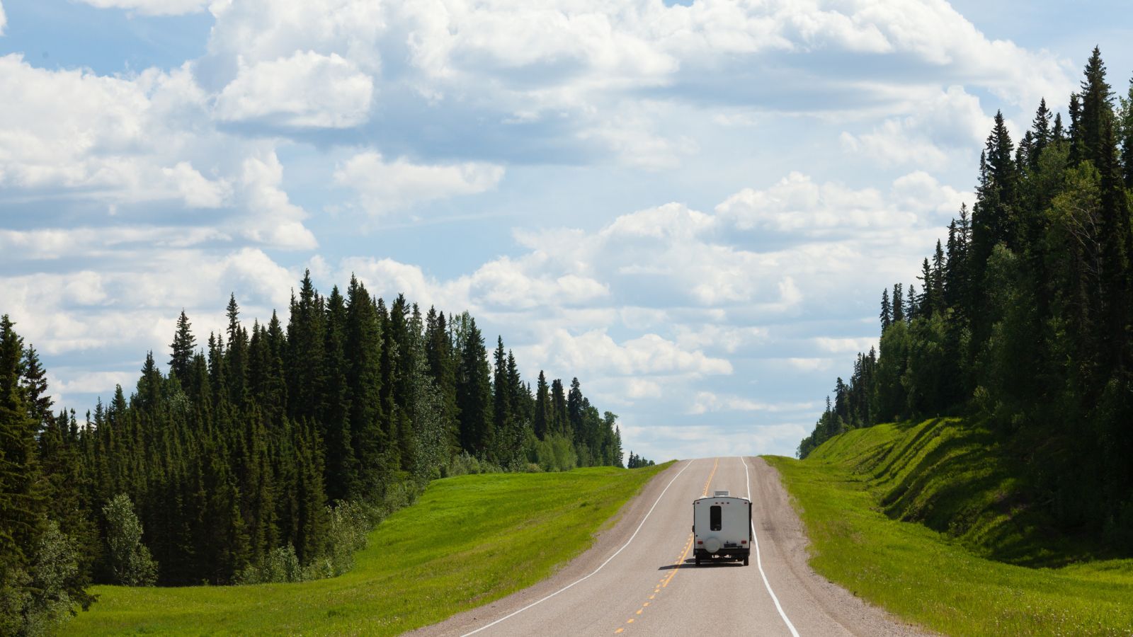 Recreational Vehicle RV on empty road of Alaska Highway, Alcan, in boreal forest taiga landscape south of Fort Nelson, British Columbia, Canada