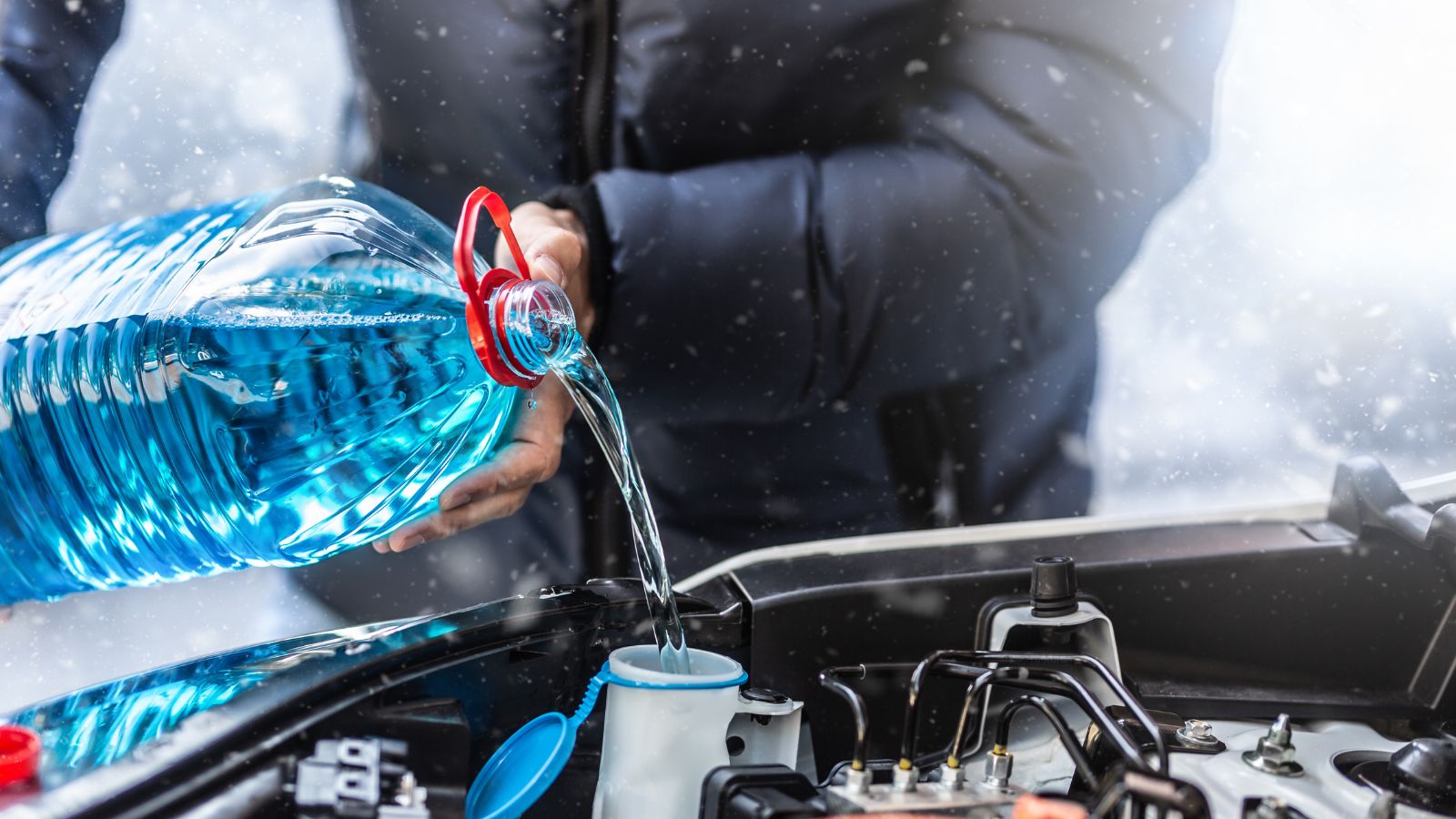 The male driver pours antifreeze into the tank to spray the windshield during a snowstorm