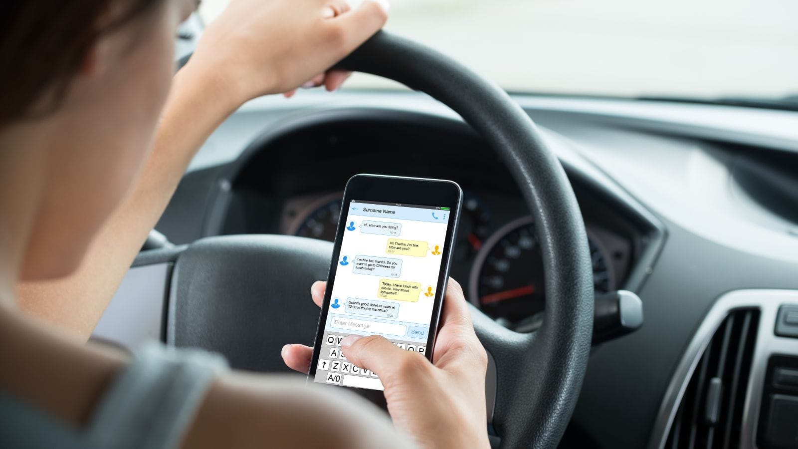 Woman Sitting Inside Car Typing Text Message On Mobile Phone