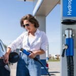 Woman holds a hydrogen fueling nozzle on a hydrogen filling station