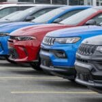 Newfoundland, Canada - March 1, 2025: A row of new blue, black, grey, and red Jeep utility vehicles on the parking lot of a car dealership. The modern vehicles are electric rechargeable automobiles.