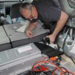 A man accessing the hybrid battery fan in 2011 Toyota Prius in order to clean it.