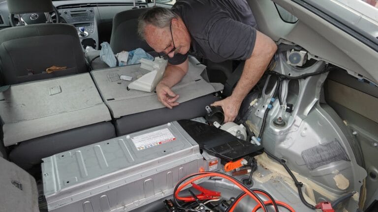 A man accessing the hybrid battery fan in 2011 Toyota Prius in order to clean it.