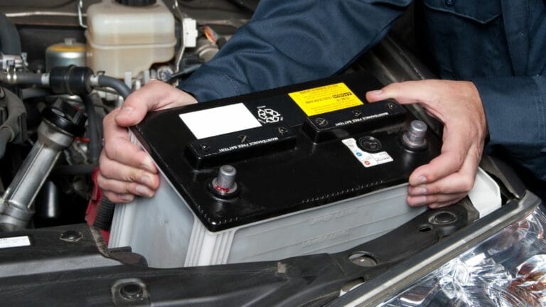 A car mechanic replaces a battery during maintenance