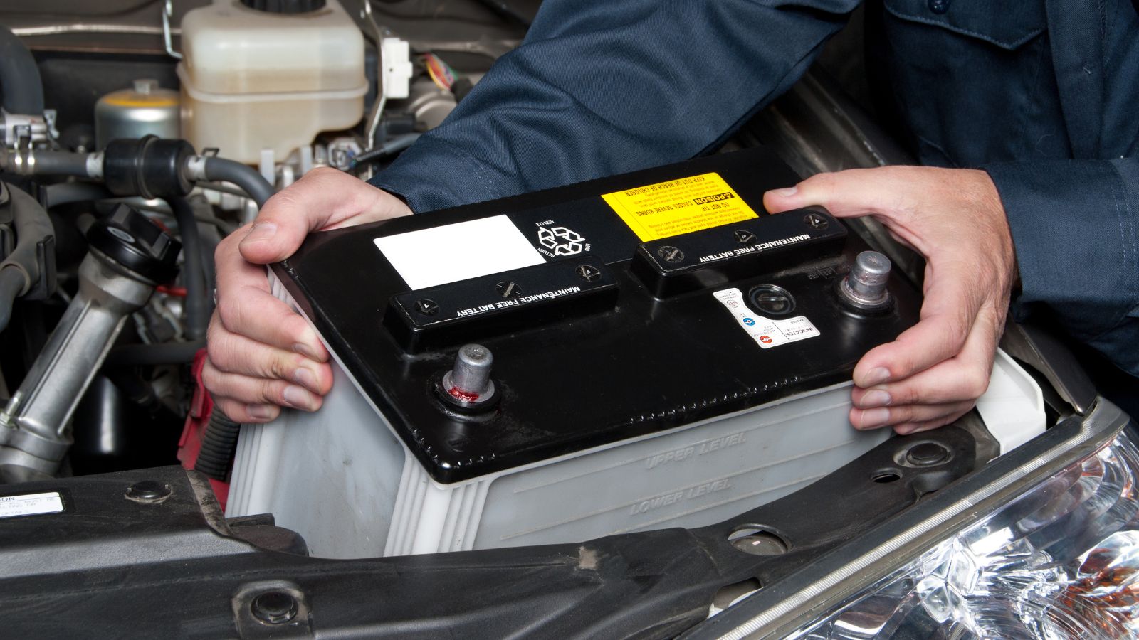 A car mechanic replaces a battery during maintenance