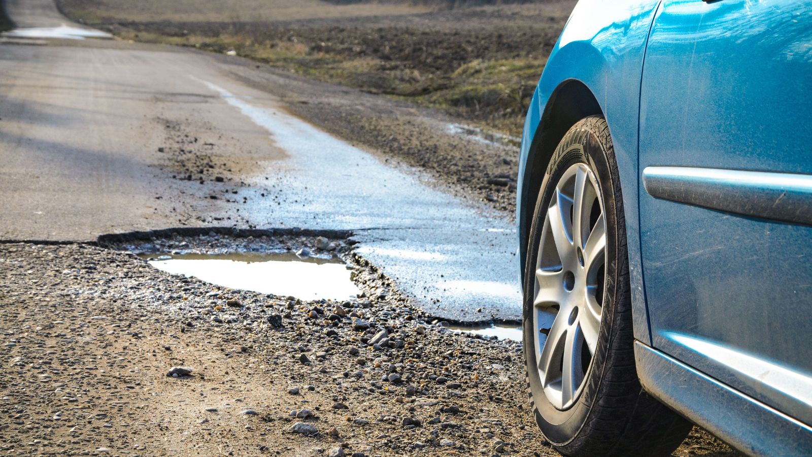 Car and winter pothole on open road