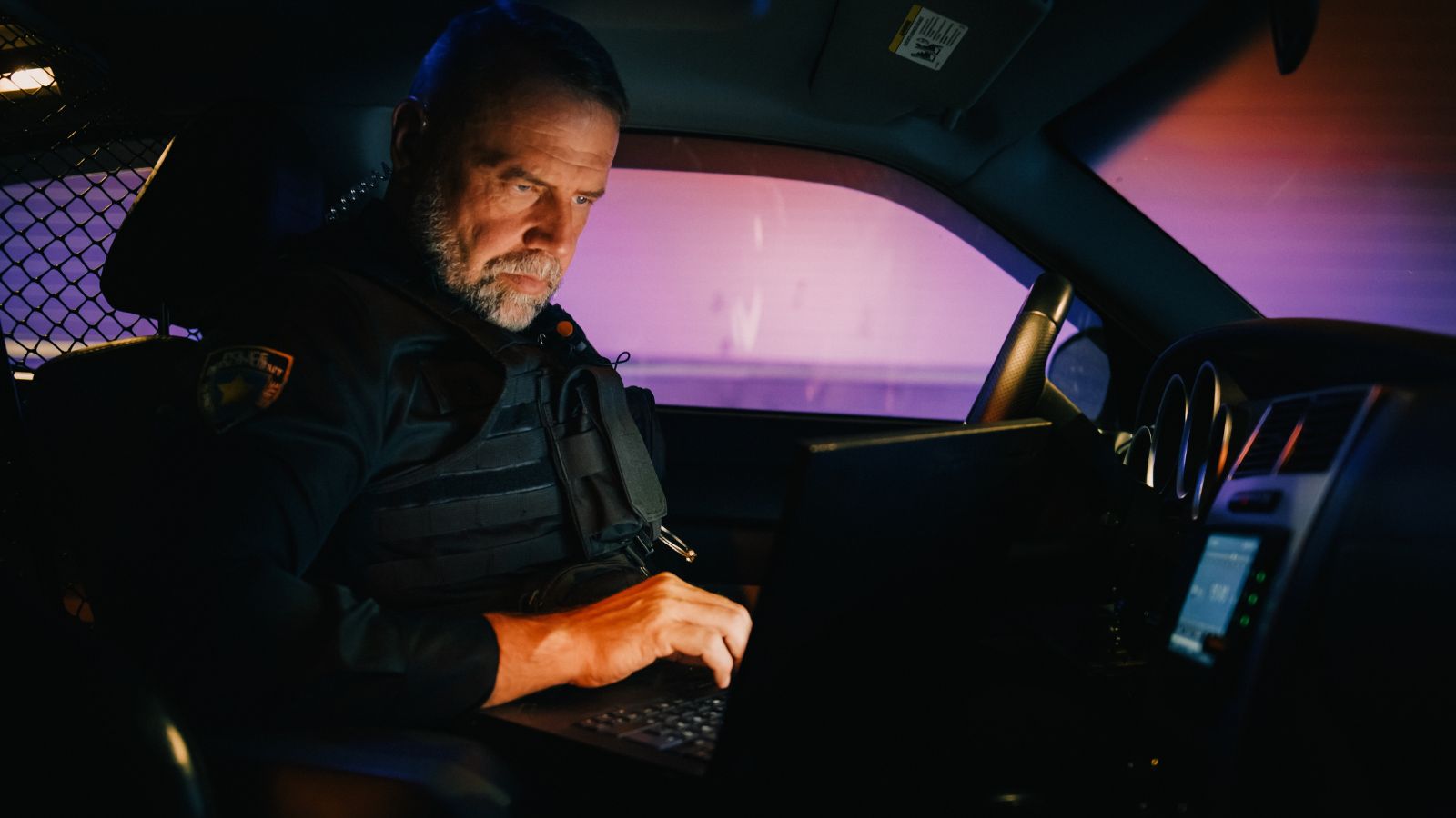 Male Police Officer on Duty Uses Laptop to Check Crime Suspect Background, License Plate, License and Registration