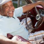 Smiling older man driving convertible, No Headrests