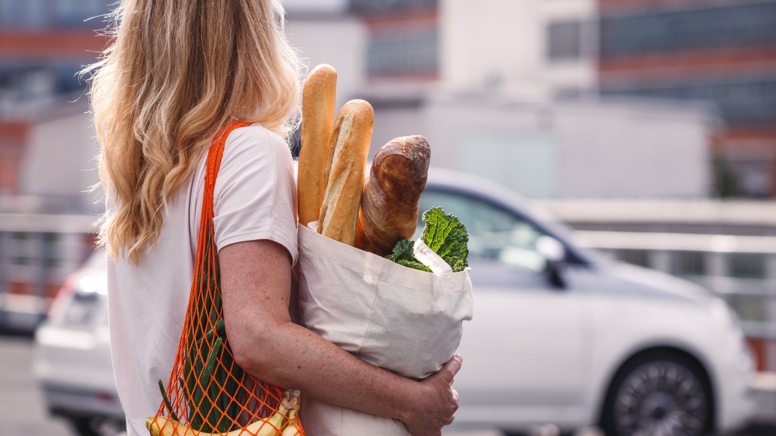 Woman with groceries walks to her car 