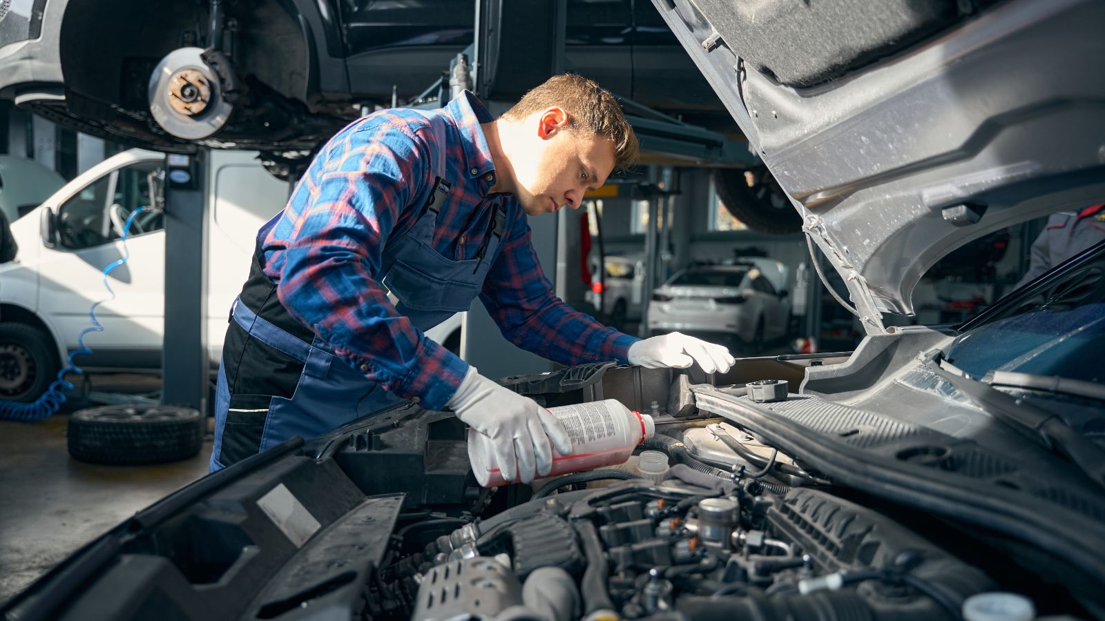 Young man adds antifreeze to cooling system