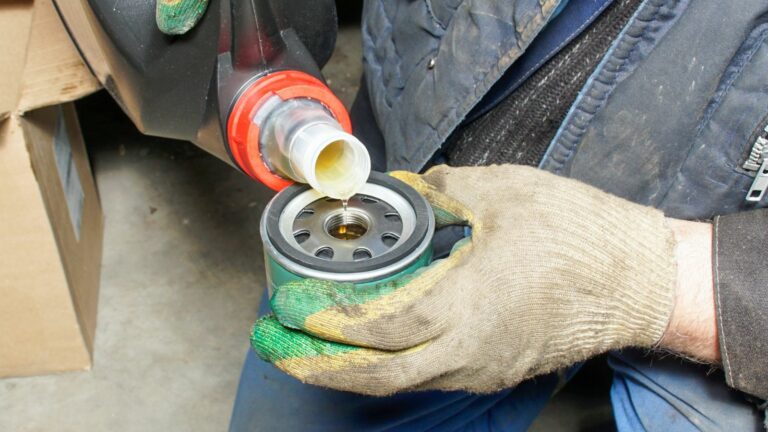 mechanic fills the filter with oil before installing it on the engine