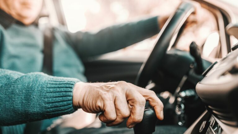 senior man holding one hand on gearshift