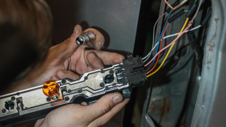 man replaces a light bulb in a car lamp